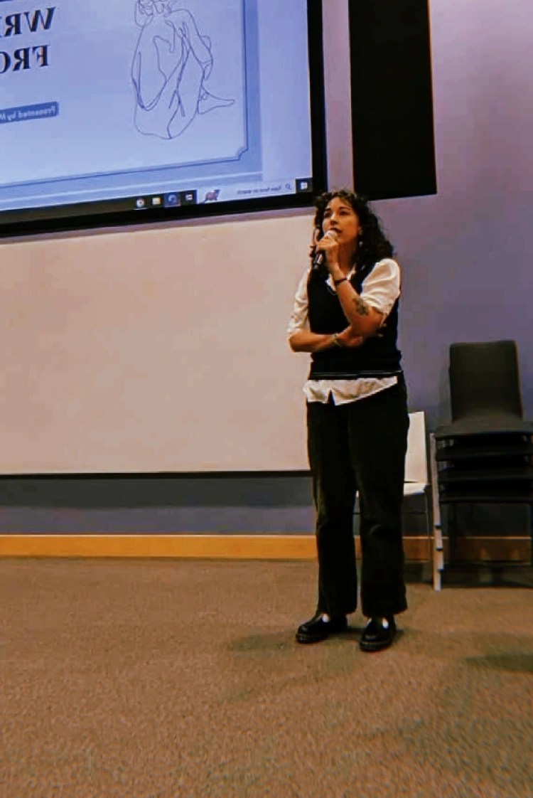 Mallory giving a presentation at the front of a lecture hall.
